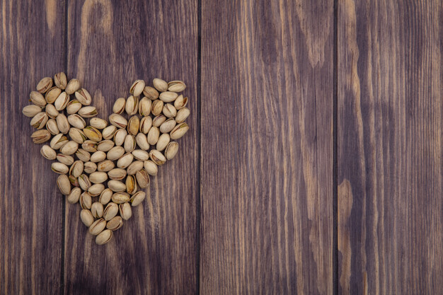 top view copy space pistachios heart shaped on wooden background